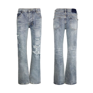 Detailed view of light blue flared jeans with ripped holes and star embroidery on pockets