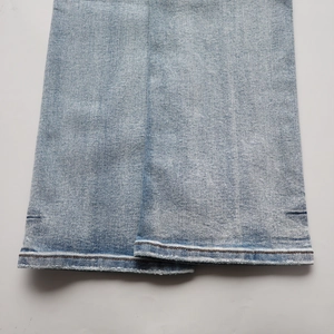 Gros plan détaillé de l'ourlet du jean bleu clair avec délavage vintage et coutures