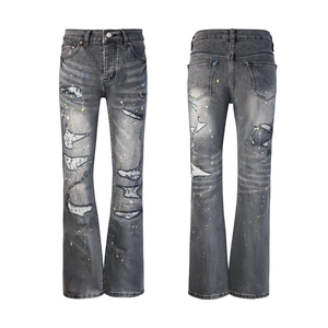 Detail view of washed grey flared denim pants with distressed holes and paint splatter