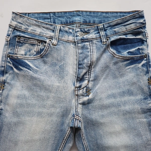 Gros plan d'un jean délavé vintage avec coutures orange et boutons métalliques fins