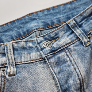 Détails de la taille d'un jean délavé bleu clair avec des surpiqûres orange contrastées