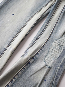Light blue distressed stack flare jeans with paint splatter and ripped details