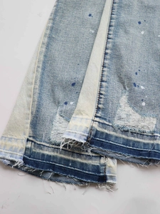Men's light blue distressed flare jeans with paint splatter and frayed hem detail