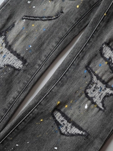 Men's dark grey washed ripped denim jeans with colorful paint splatters and patches