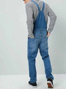 Detail view of denim overalls showing cross-back straps and functional back pockets