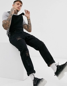 Close-up of black denim overalls featuring distressed ripped details and a streetwear style