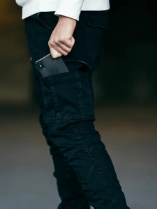 Détail d'une grande poche cargo latérale sur un jean utilitaire noir offrant un espace de rangement