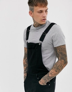 Detail of black denim dungarees with front pocket and metal adjustable buckles on straps