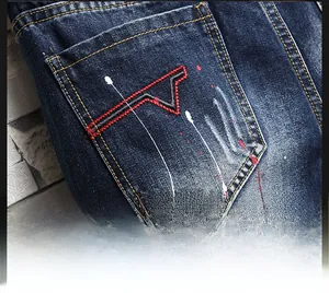 Close-up of men's blue denim shorts featuring red embroidery and white paint splatters