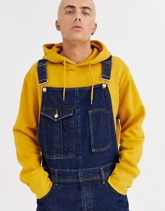 Detail of dark blue denim overalls with front double pockets and metal buckles