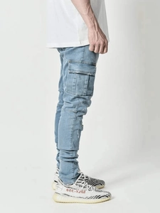 Détail du jean slim bleu clair avec poches cargo latérales tactiques et délavage léger