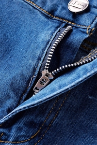 Close-up of blue denim jeans featuring a silver metal button and durable copper zipper