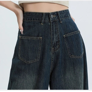 Detail van donkerblauwe jeans met hoge taille, grote opgestikte zakken en knopen