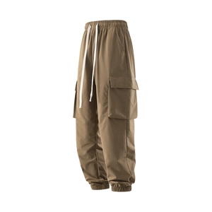 Detail of khaki cargo pants featuring elastic waist with bold white drawstring and side pockets