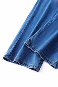 Detail of blue stretch denim jeans showing yellow stitching and durable hem texture