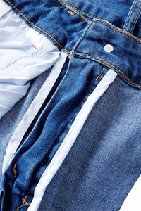 Detail of blue stretch denim jeans showing inner waistband, silver button and stitching