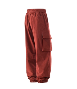 Detail view of cargo pants with large side flap pockets and elastic cuffs in rust red