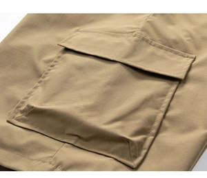 Detail of khaki ripstop fabric showing cargo pocket texture and durable stitching