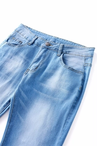 Macro view of light blue denim jeans showing whiskering effect and J JEANS button detail