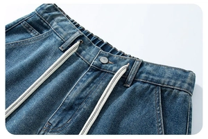 Dettaglio vita elastica con coulisse bianca e bottone in metallo su pantaloncini denim