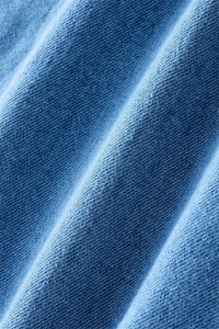 Macro shot of light blue stretch denim fabric texture with twill weave and soft fringe detail