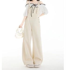 Detail der lockeren beigen High-Waist Jeans-Latzhose mit seitlichen Metallknöpfen und Tasche