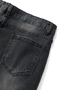 Detailed close-up of dark grey denim jeans showing rear pockets and washed cotton texture