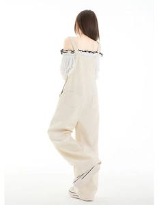 Detailansicht der beige weiten Latzhose mit Gesäßtaschen und schulterfreier Bluse