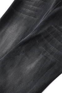Detailed close-up of charcoal black washed denim fabric with subtle twill texture and fading