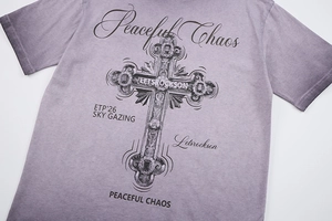 Dettaglio della grafica a croce vintage e scritte artistiche su maglietta streetwear di cotone