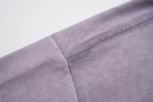 Dettaglio della doppia cucitura sulla spalla di una t-shirt in cotone viola lavato vintage