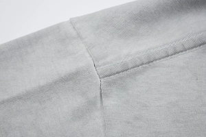 Close-up of double-stitched shoulder seams on a gray washed vintage cotton t-shirt