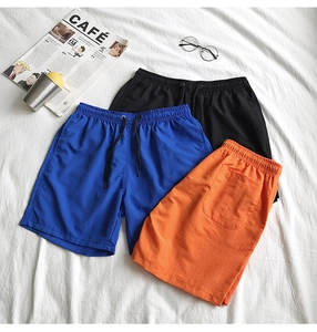 Vue à plat de shorts d'été à séchage rapide noirs, bleus et oranges avec cordon de serrage
