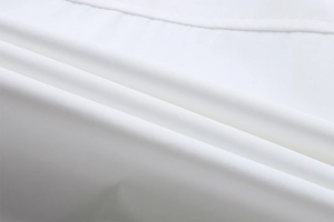 Macro shot of white textile fabric texture showing smooth plain weave and fine stitching