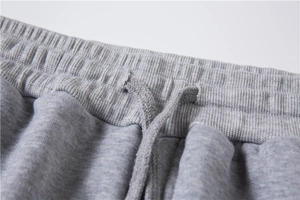 Dettaglio dell'elastico in vita a costine e della coulisse intrecciata sui pantaloni grigi