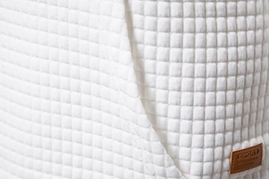 Detailed macro view of white waffle textured fabric with a brown leather sport label