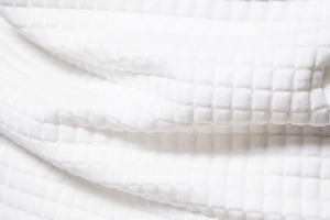 Macro view of white quilted waffle texture fabric with clean 3D square pattern details