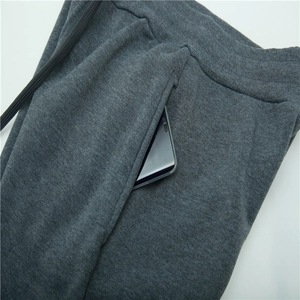 Detail of dark grey sweatpants with elastic waist, drawstring and deep side pockets
