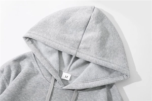 Detailaufnahme von hellem grauem Hoodie mit feiner Stoffstruktur, Kordelzug und M-Etikett