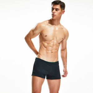 Close-up of men's low waist swim trunks in black with green contrast waistband detail