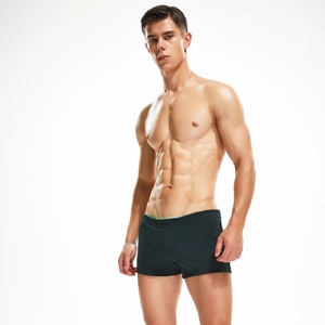 Detail of men's black low waist swim trunks with light green trim and elastic fabric