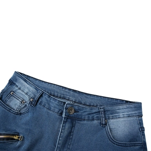 Gros plan d'un jean bleu délavé montrant le bouton en métal et le détail de la poche