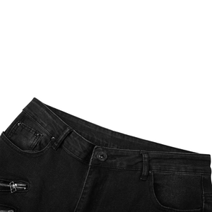 Détail d'un jean biker noir délavé avec bouton métallique et poches zippées décoratives