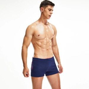 Detail view of navy blue tight-fit men's swim trunks with pink contrast piping trim