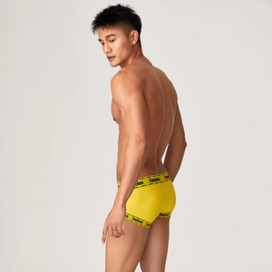 Detail of men's bright yellow trunks featuring a creative Caution warning waistband