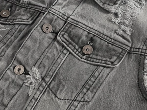 Dettaglio ravvicinato del gilet in denim grigio con bottoni in metallo e strappi