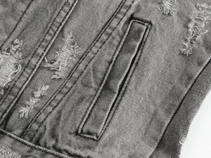 Dettaglio del gilet in denim grigio con effetti usurati, tasche e cuciture doppie forti