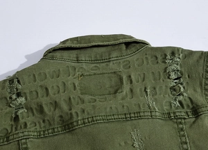 Close-up of military green denim vest showing distressed ripped texture and embossed text