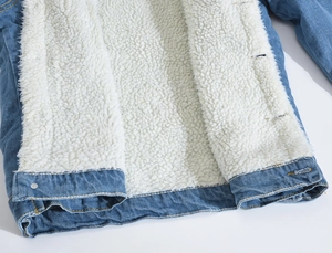 Detailed close-up of men's blue denim jacket with warm white faux lamb wool lining and stitching