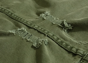Close-up of army green denim fabric with distressed edges and heavy twill texture